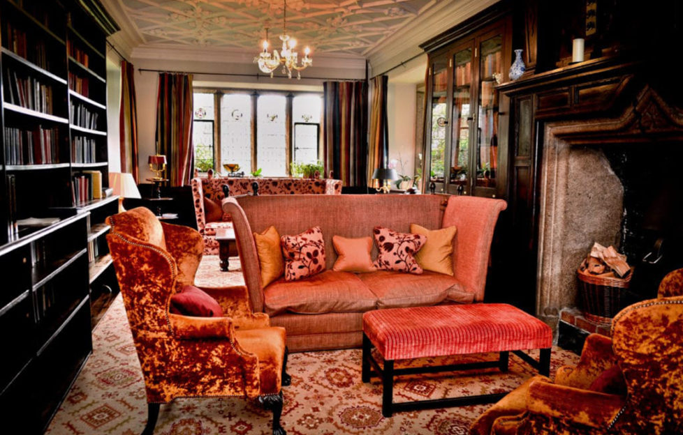 The drawing room at Lewtrenchard Manor, dark wood, mullioned window and orange velvet sofas