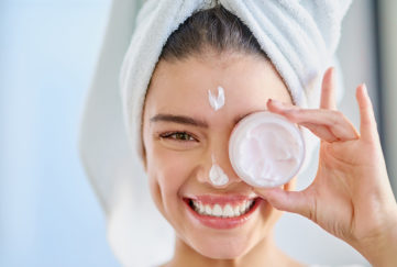 Woman with moisturiser packaging covering her eye Pic: Istockphoto