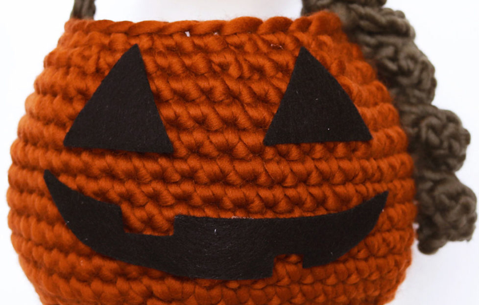 Close up of orange crocheted basket with felt features to resemble a pumpkin lantern