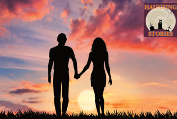 Young couple holding hands silhouetted against colourful sunset sky