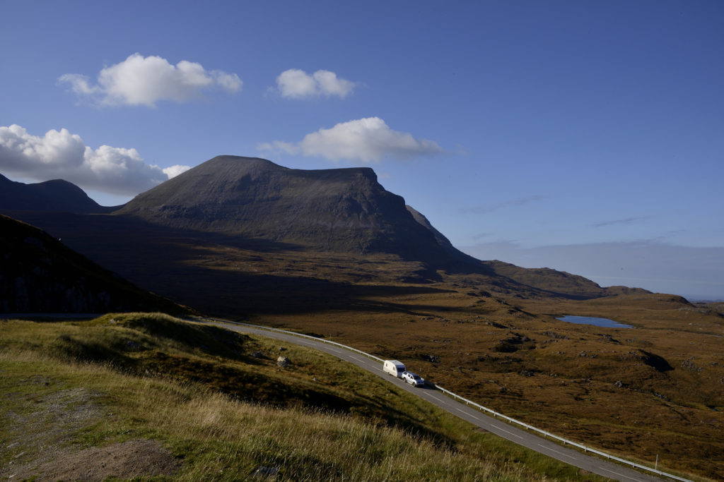 Car pulling a caravan through a mountain range