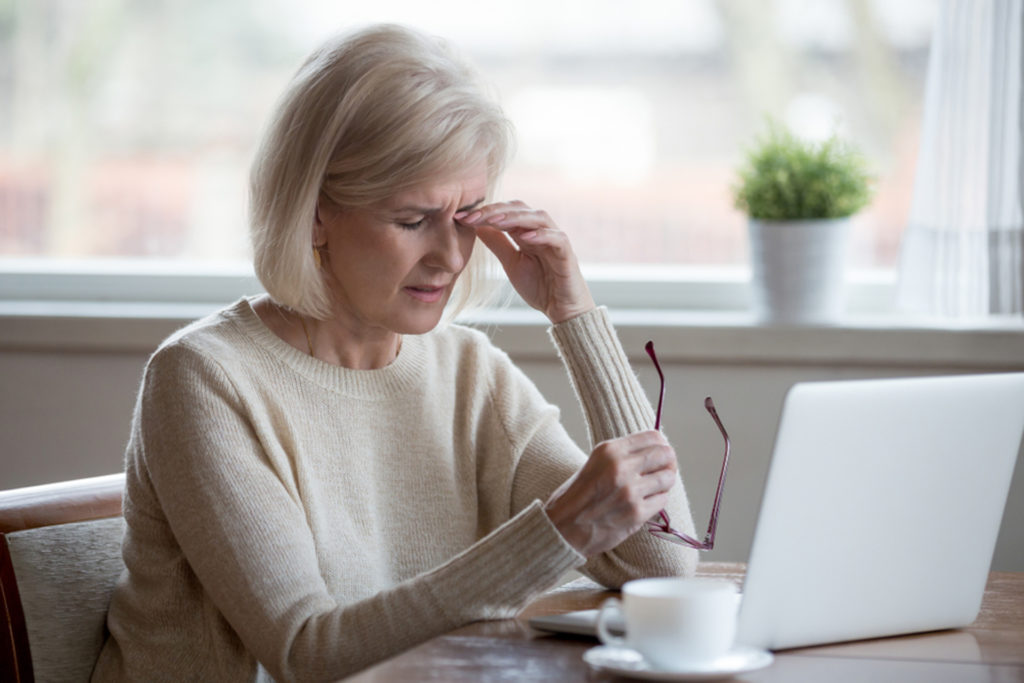 Woman sitting at laptop rubbing her eyes