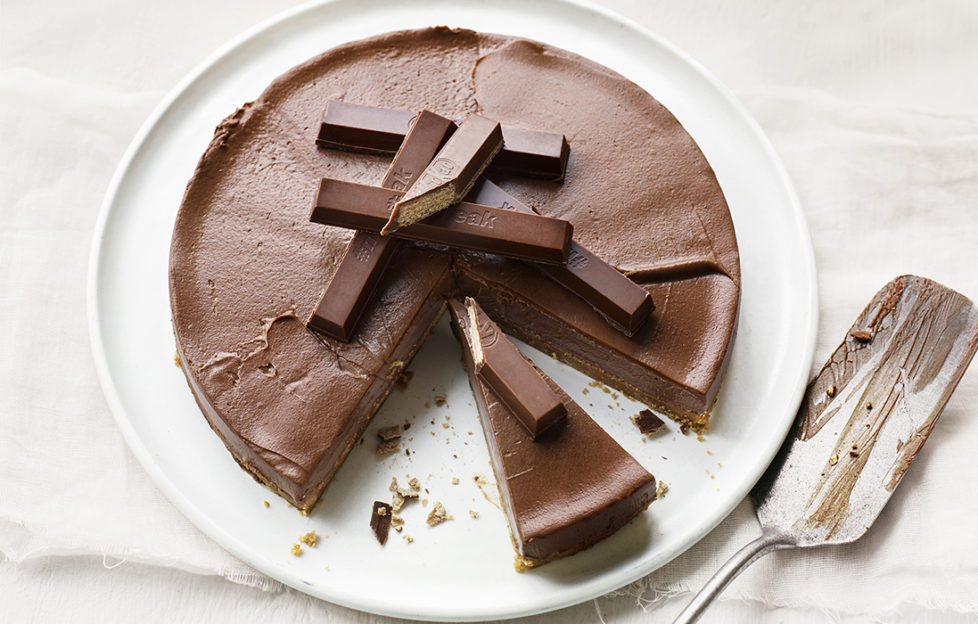 Chocolate cheesecake decorated with KitKat fingers, several slices cut