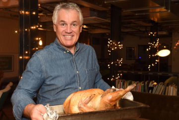 Paul Kelly smiling holding roasting tray with cooked turkey