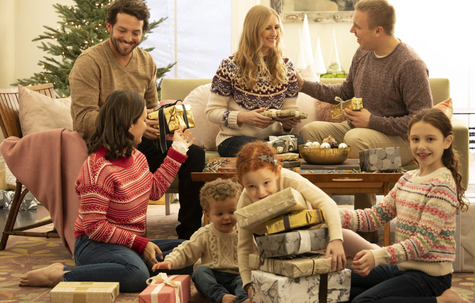 Family opening presents at Christmas in living room