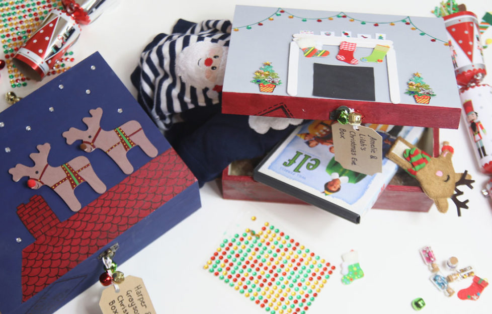 Decorated wooden boxes filled with goodies for Christmas Eve, including Elf DVDand hot water bottle cover