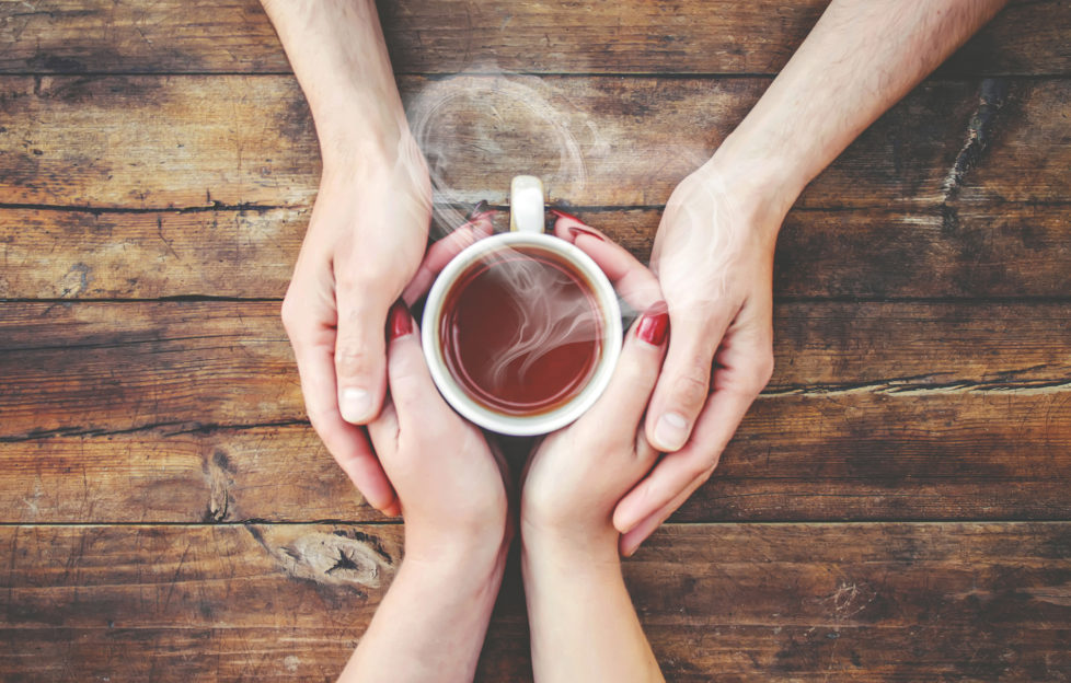 A cup of tea in the hands of a man and a woman for health benefits kindness