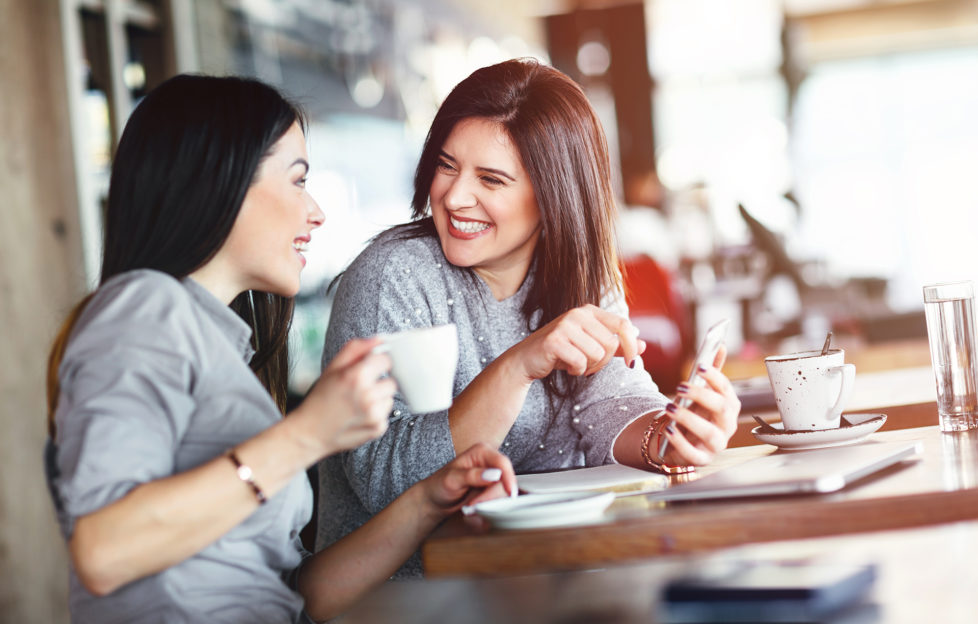 Two smiling women chatting in cafe