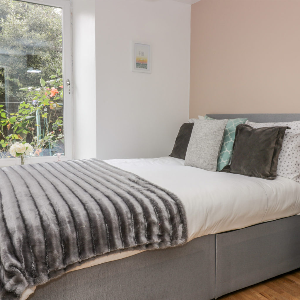Smart, comfortable double bed by window looking on to cottage garden