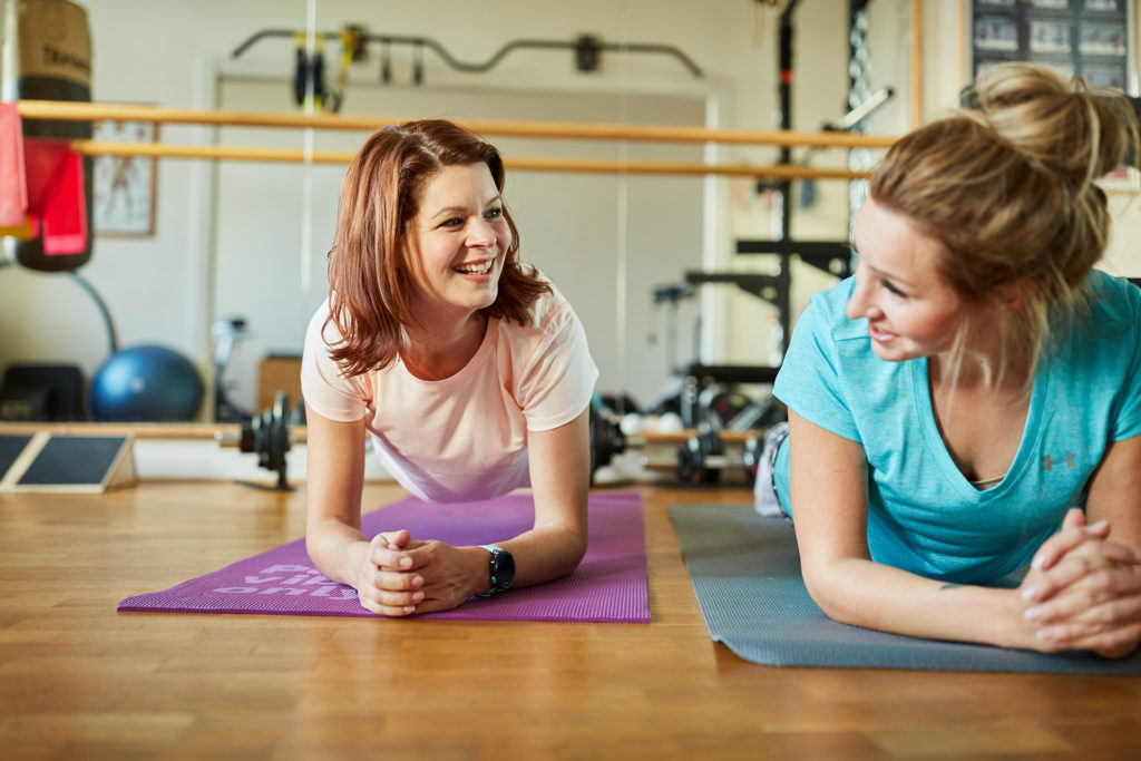 2 women lying face down on exercise mats