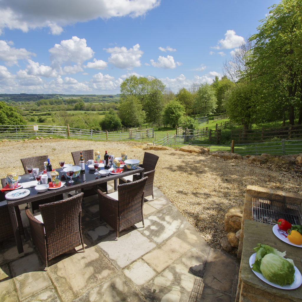 Good quality outdoor furniture, table set for 6 with salad buffet on side, all on wide area of flags and gravel overlooking rolling hills and woods