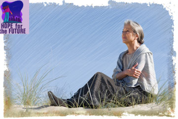 Mature woman sitting on sand dune, looking out to sea, sea grass in foreground