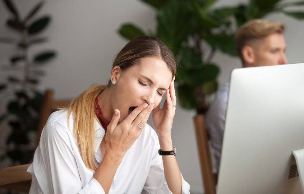 Bored tired businesswoman yawning at workplace feeling lack of sleep