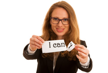 Keeping new year resolution. Smiling woman holding out paper that says "I can't", she is tearing off the end to leave "I can"