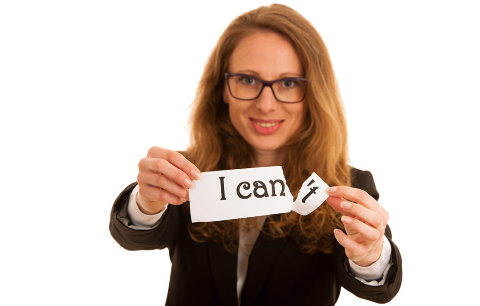 Keeping new year resolution. Smiling woman holding out paper that says "I can't", she is tearing off the end to leave "I can"