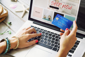Woman's hands, typing on laptop and holding credit card