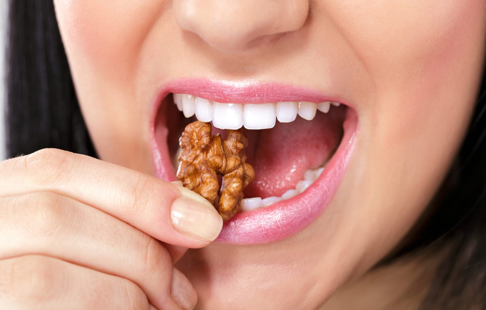 Close up of a woman's mouth eating a nut