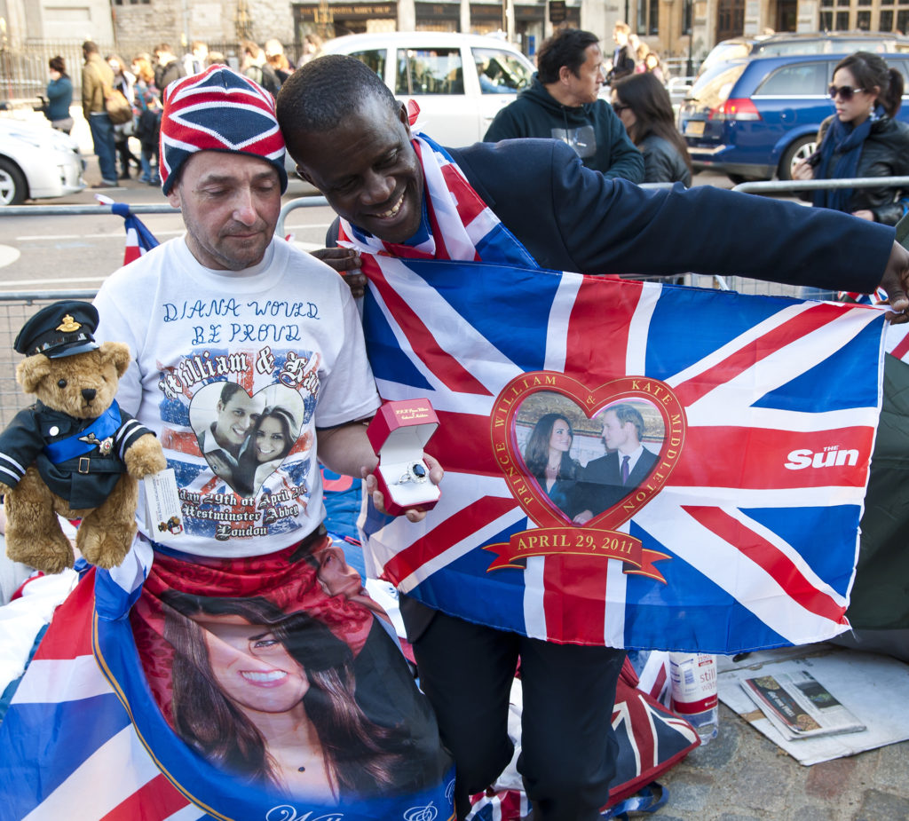 Two men hold up Union Jack flags with a heart shaped picture of William and Kate in the middle, on the street outside Westminster Abbey
