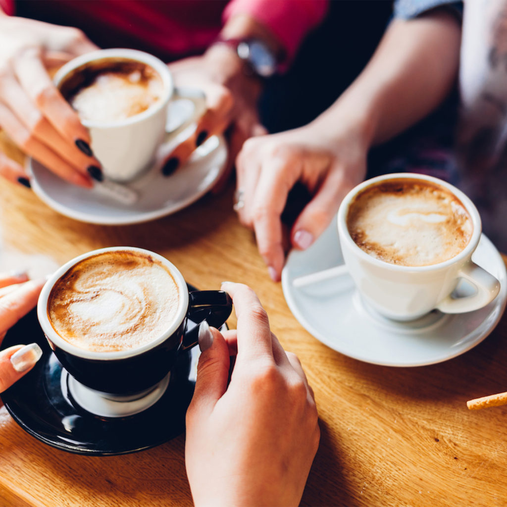 Three people sitting at a table with cups of coffee