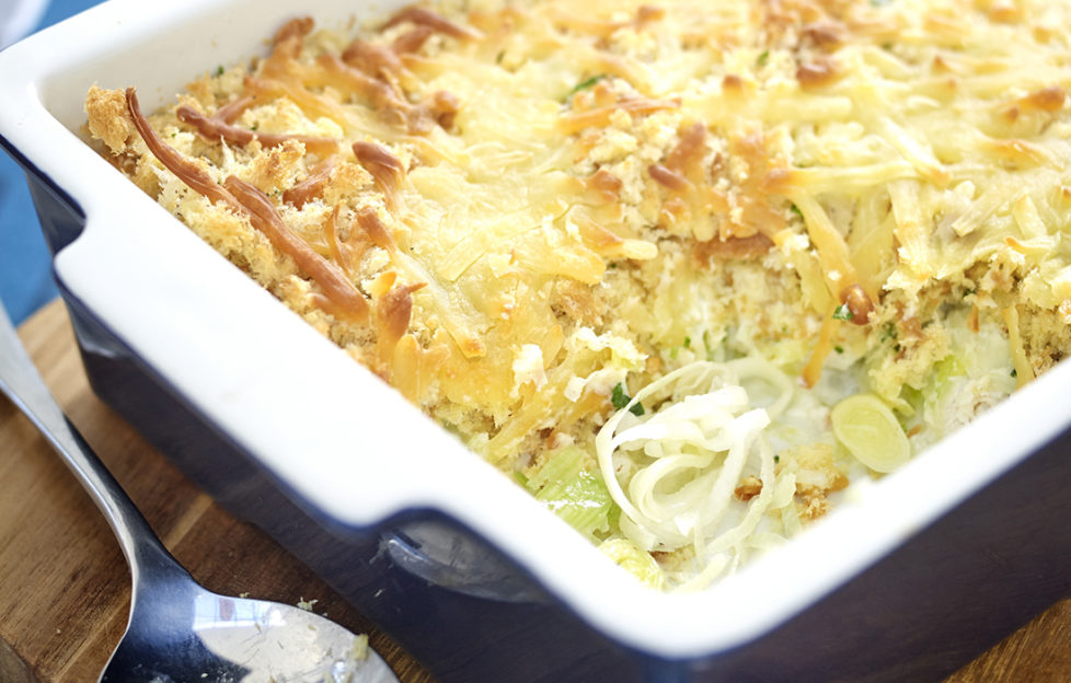 Golden cheese topped bake, spoonful removed showing leek and chicken