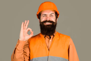 Tradesperson in orange hard hat and hi-vis vest giving OK symbol with finger and thumb