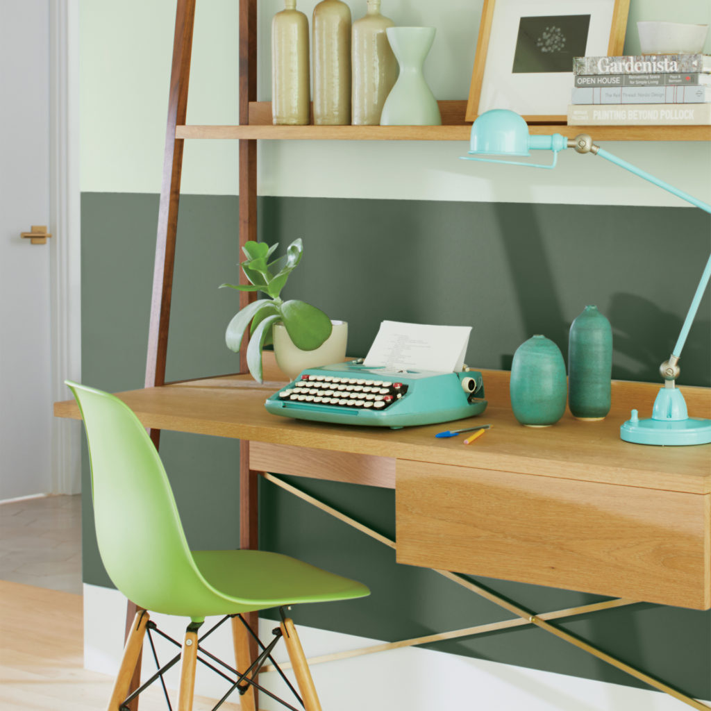 Mini office with green chair, retro green typewriter, jade coloured vases and lamp against 2 tone green wall