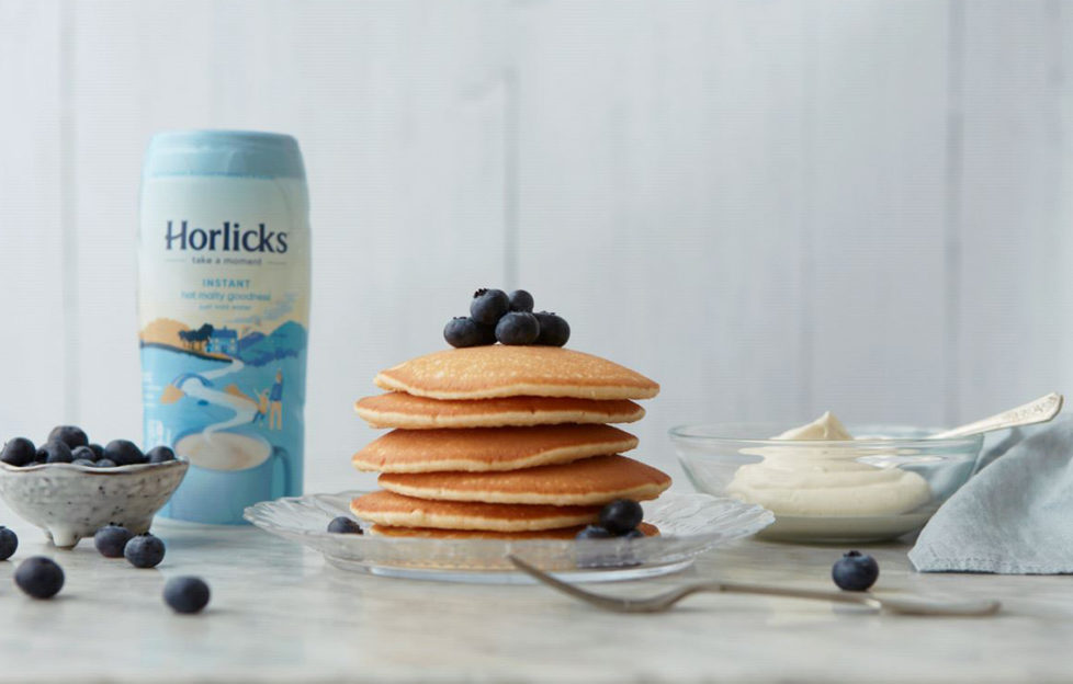 Pile of pancakes topped with fresh blueberries, jar of Horlicks Light