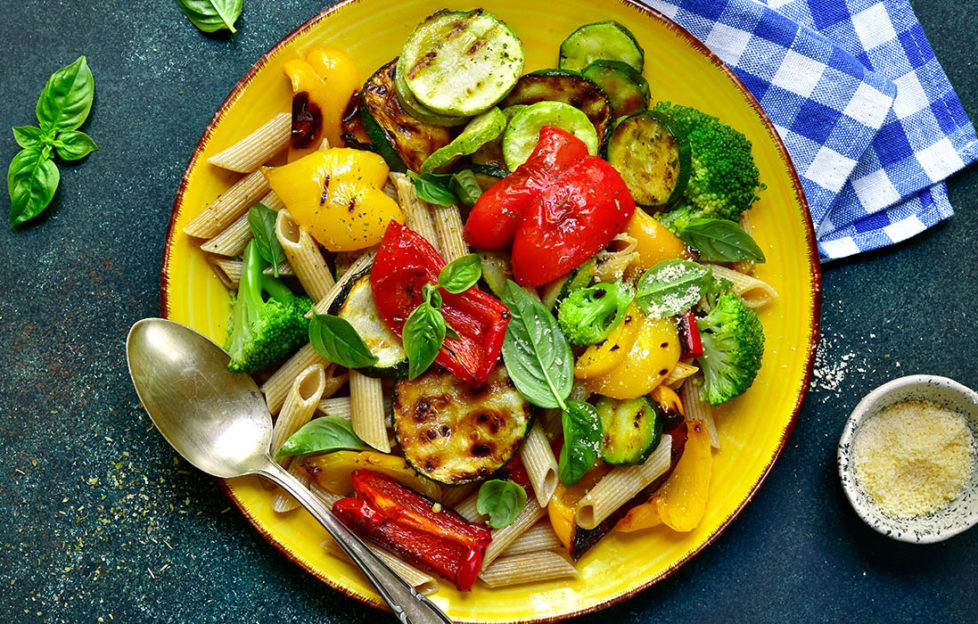 Plate of pasta bake and roasted or grilled pepper and courgette, garnished with fresh basil leaves