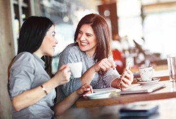 2 smiling women having chat in cafe