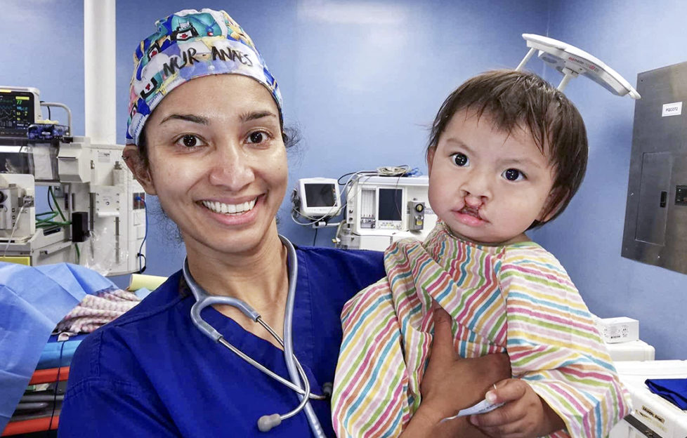 Smiling nurse with toddler who has just had a cleft lip operation, red scars above lip