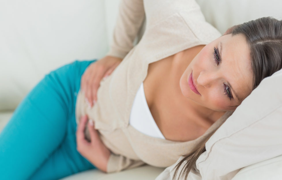 Woman lying on sofa with sore tummy