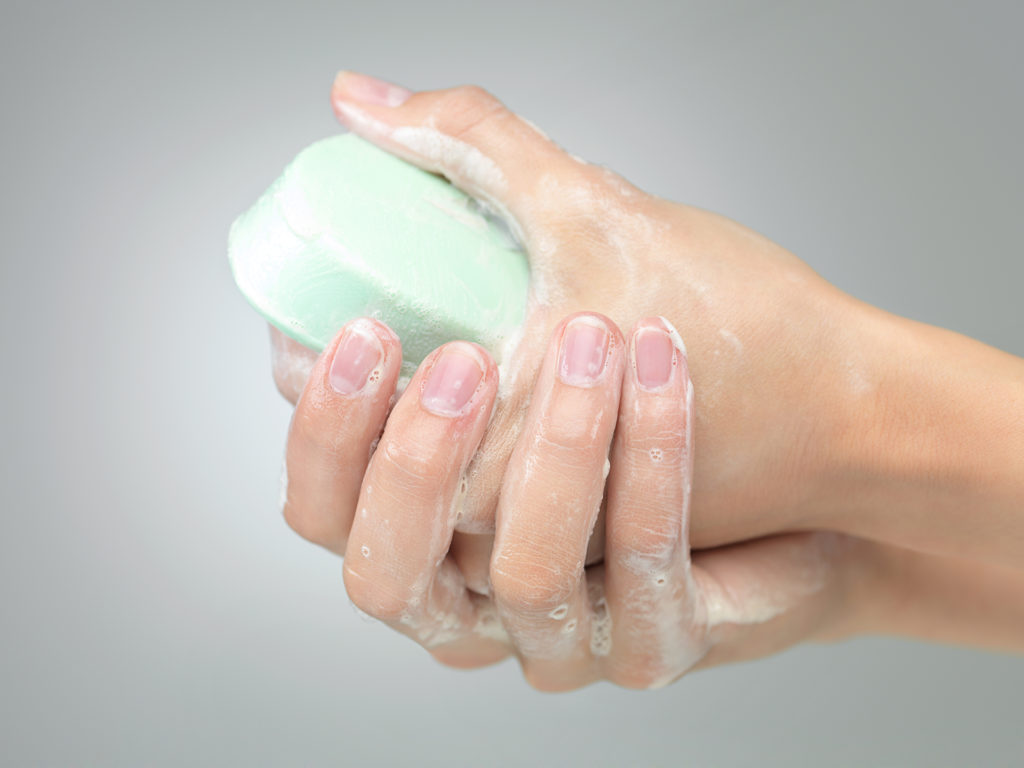 Woman washing her hands with green bar of soap