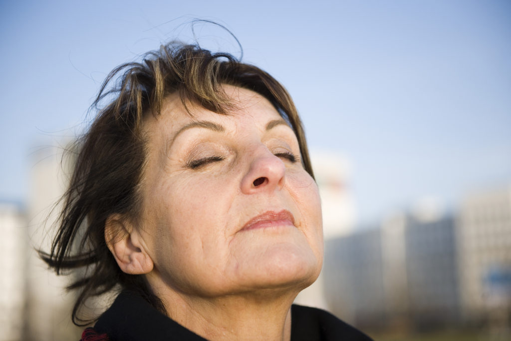 Woman outdoors taking a deep breath