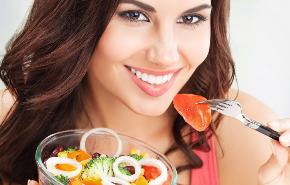 Dark haired woman eating salad