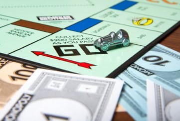 Go square of Monopoly board with car player token and Monopoly money visible