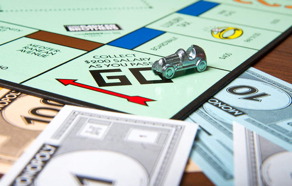 Go square of Monopoly board with car player token and Monopoly money visible