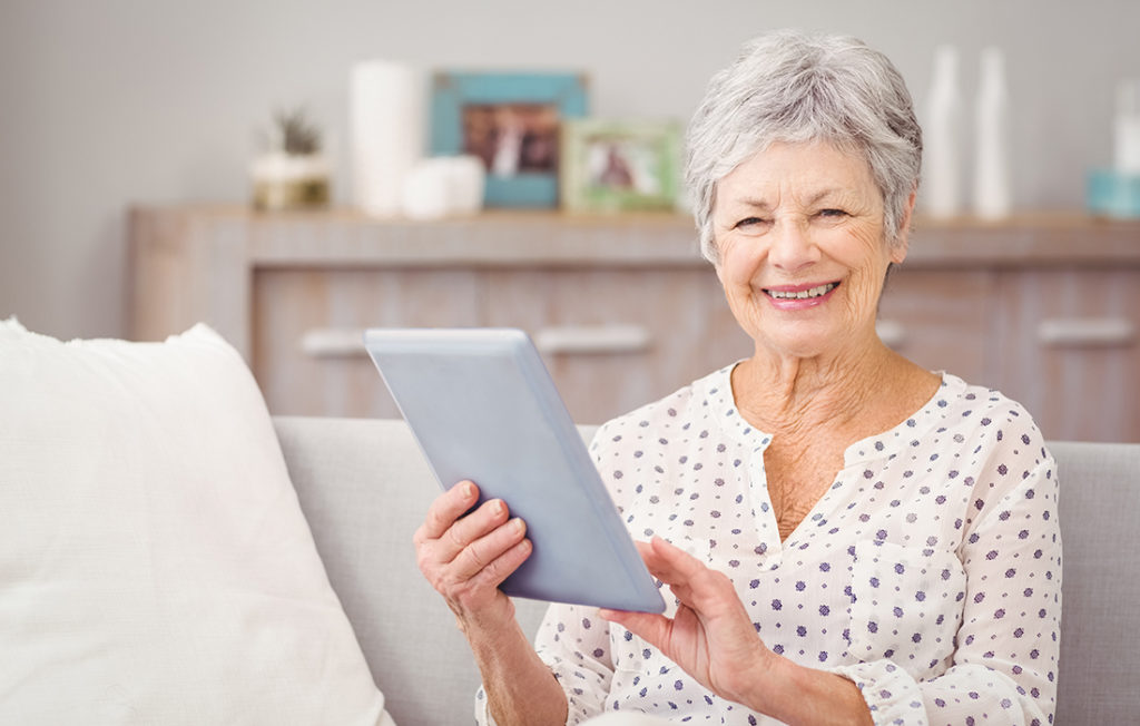 Mature woman holds up computer tablet and smiles