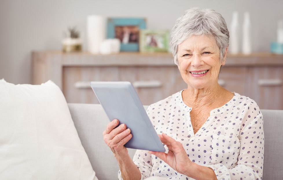 Mature woman holds up computer tablet and smiles