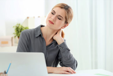 Beautiful woman suffering from neck pain in office