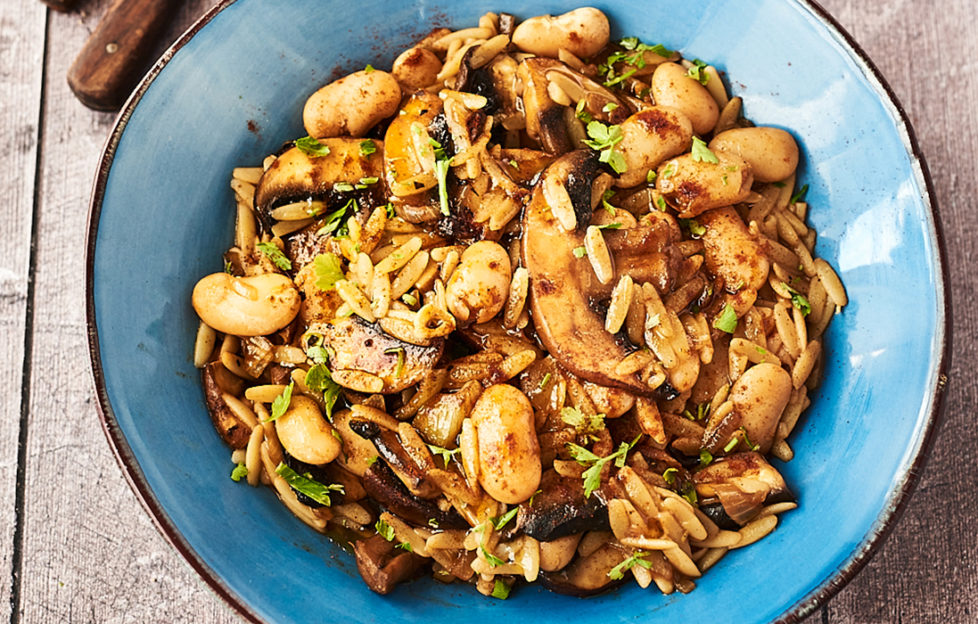 Turquoise bowl of sliced mushrooms, butterbeans, orzo pasta and vegetables in a rich golden brown sauce