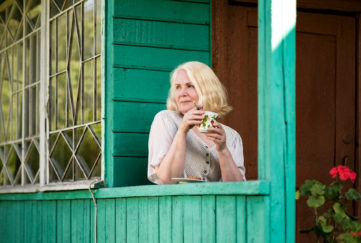 Senior blonde european woman resting and drinking tea sitting on summer house terrace. Have a rest during vacation;