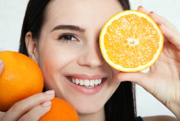 Woman with oranges close-up to her face.
