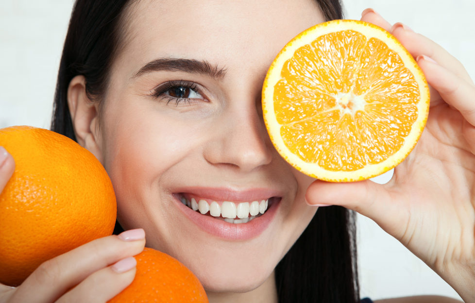 Woman with oranges close-up to her face.
