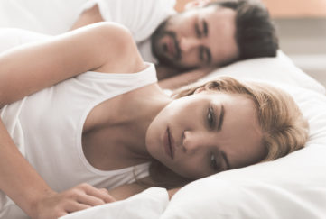 Anxious girl cannot sleep near her husband in bedroom;