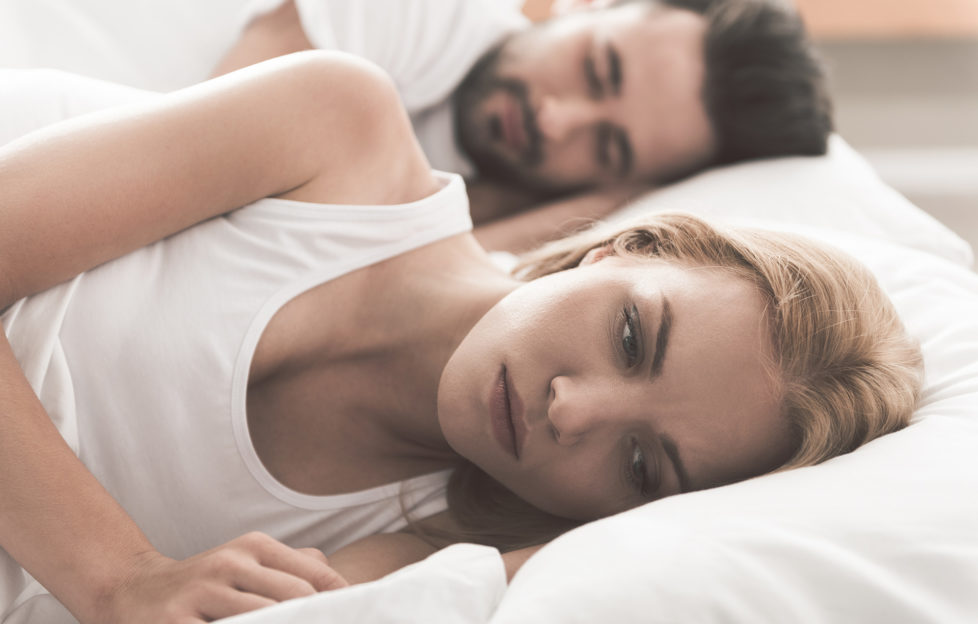 Anxious girl cannot sleep near her husband in bedroom;