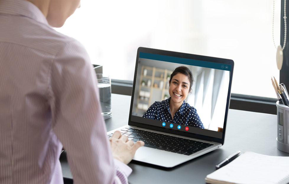 Woman chatting to smiling counsellor on screen