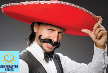 Man in red sombrero, bad fake Mexican moustache, bow tie and waistcoat, striking a pose