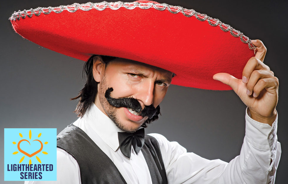 Man in red sombrero, bad fake Mexican moustache, bow tie and waistcoat, striking a pose