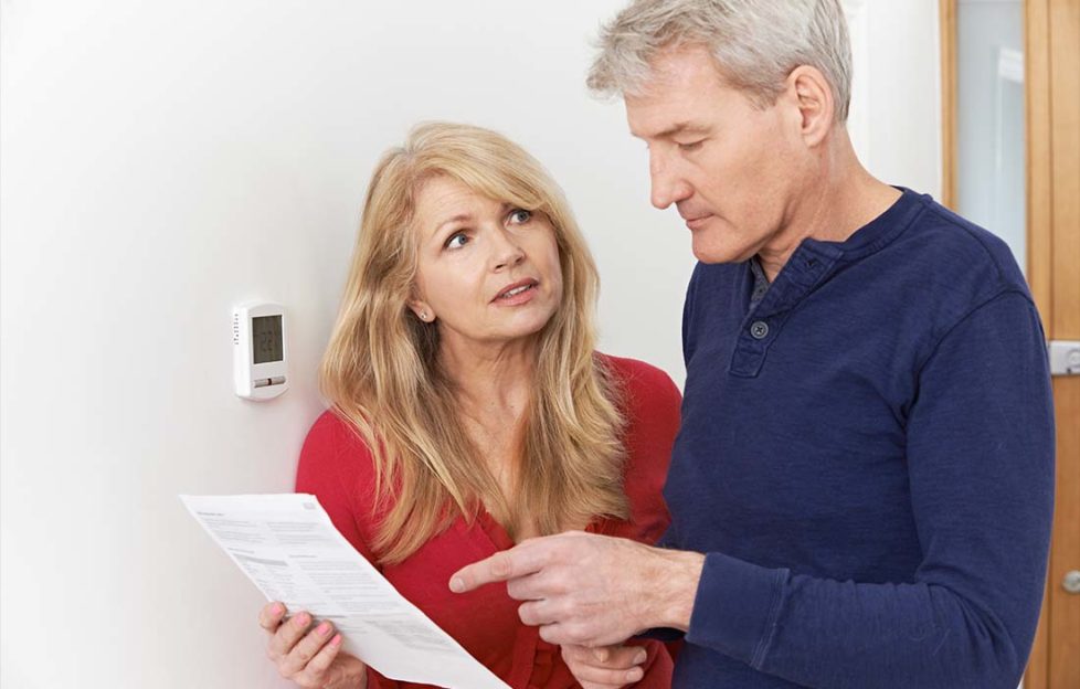 Worried Mature Couple With Bill Turning Down Central Heating