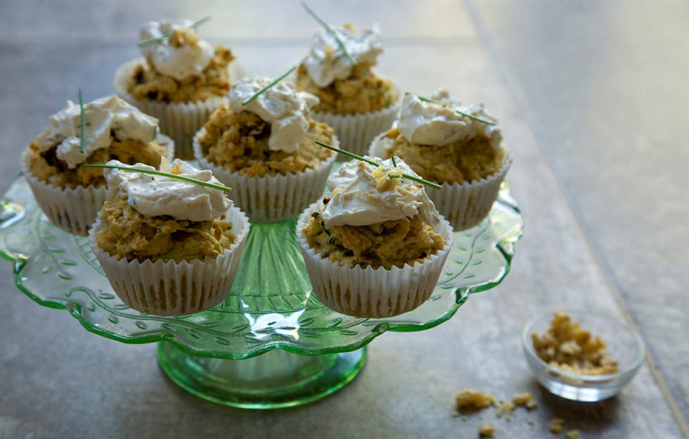 Green glass cake stand, 7 vegan cupcakes topped with a dollop of cream cheese and a chive stalk